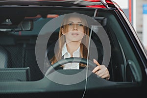 Photo of happy young woman sitting inside her new car. Concept for car rental.
