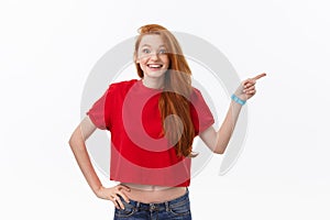 Photo of happy young woman standing isolated over white wall background. Looking camera showing copyspace pointing