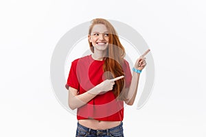 Photo of happy young woman standing isolated over white wall background. Looking camera showing copyspace pointing