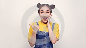 Photo of happy young woman standing isolated over white wall background. Looking camera showing copyspace pointing