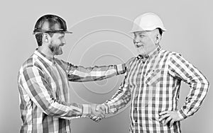 photo of helmet. partners men handshaking isolated on yellow. partners men handshaking in studio. partners men