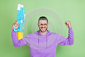 Photo of hooray millennial brunet guy hold watergun wear spectacles hoodie isolated on green color background