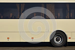 Photo of the hull of a large and long yellow bus with free space for advertising. Close-up side view of a passenger vehicle for t