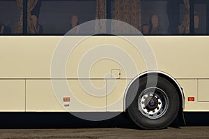 Photo of the hull of a large and long yellow bus with free space for advertising. Close-up side view of a passenger vehicle for t