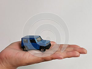 Photo of human hand with miniature car  on white background.