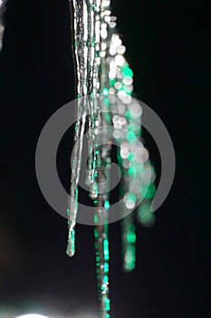 Photo icicles group on a dark background, illuminatet with neon green light