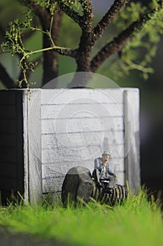 Photo Illustration, Sitting Hopeless Sad Old Man Mini Figure Toy under the tree