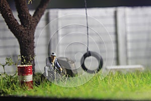 Photo Illustration, Sitting Hopeless Sad Old Man Mini Figure Toy under the tree