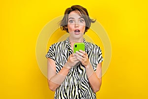 Photo of impressed astonished cute girl with hold smartphone facebook twitter instagram whatsapp isolated on yellow