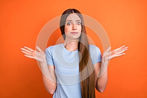 Photo of impressed brown hairdo millennial lady shrug shoulders wear blue t-shirt isolated on vivid orange color