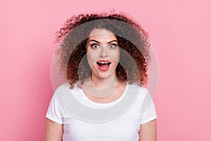 Photo of impressed ecstatic woman with perming coiffure dressed white t-shirt staring at awesome offer isolated on pink