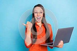 Photo of impressed funny woman wear red shirt arm spectacles holding modern device pointing empty space isolated blue