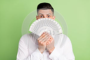 Photo of impressed funny young guy dressed white shirt money fan cover mouth isolated green color background