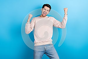 Photo of impressed optimistic man stylish haircut dressed beige pullover clenching fists win betting isolated on blue