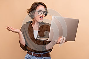 Photo of impressed stupor girl dressed brown shirt eyewear having working problem modern gadget isolated beige color