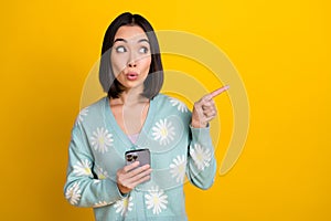 Photo of impressed woman hold phone look indicating empty space instagram facebook twitter whatsapp  on yellow