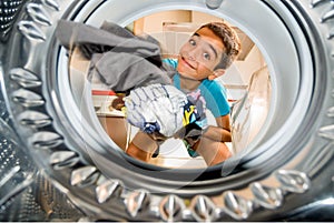 Photo from inside a washing machine of a boy putting clothes