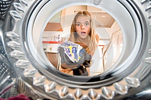 Photo from inside a washing machine where you see a girl putting clothes