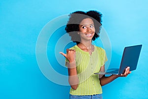 Photo of interested positive girl perming coiffure green t-shirt hold laptop indicating empty space isolated on blue