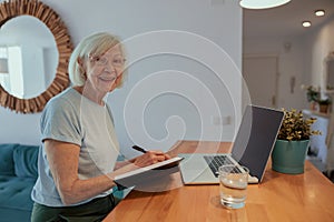 Photo of joyful aged woman with laptop indoors