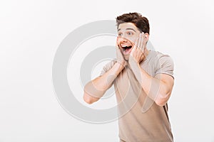 Photo of joyful brunette guy yelling and grabbing his face like