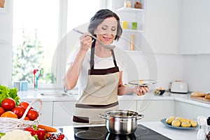 Photo of joyful happy positive old woman smile taste spoon soup pan enjoy healthy food indoors inside house home