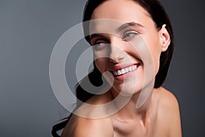 Photo of joyful smiling woman with brunette curls lokk empty space  grey color background