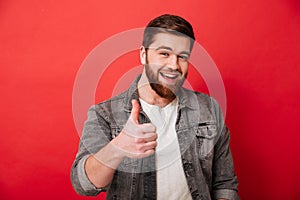 Photo of joyous bearded guy 30s in jeans jacket smiling and show