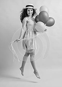 photo of jumping summer woman with balloons wearing hat. summer woman with balloons