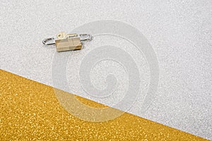 Photo of a key and two small padlocks on a gold and silver background that is intended to show a concept.The photo has copy space