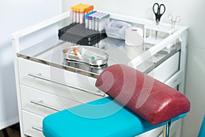 Photo of a laboratory with a patient's chair and a table with a medical tray with a syringe and test tubes for taking