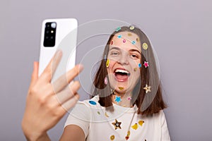 Photo of laughing woman blogger covered with funny stickers making selfie having video call broadcasting livestream posing