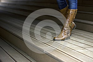 Photo of leather woman`s with boots on wooden trail