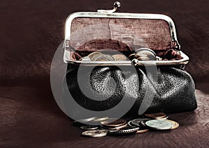 Photo of a leathier purse full of coins on table