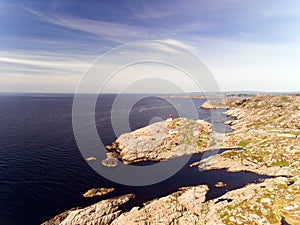 Photo of Lindesnes beacon in summer, South Norway. Aerial shot. Rocky sea coast and blue sky.