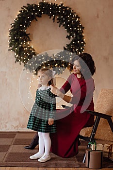 Photo of a little beautiful girl and her mother with a Christmas wreath