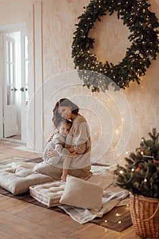 Photo of a little beautiful girl and her mother with a Christmas wreath