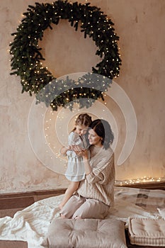 Photo of a little beautiful girl and her mother with a Christmas wreath