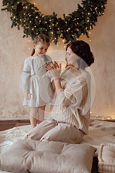 Photo of a little beautiful girl and her mother with a Christmas wreath