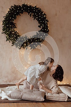 Photo of a little beautiful girl and her mother with a Christmas wreath