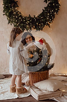 Photo of a little beautiful girl and her mother with a Christmas wreath