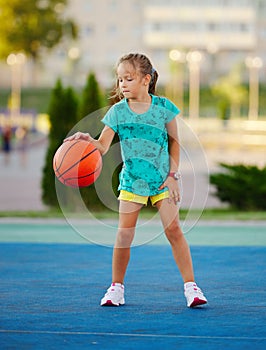 Photo of little cute girl playing basketball outdoors