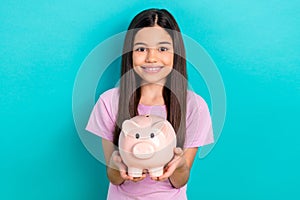 Photo of little cute preteen schoolgirl kid hold piggy bank wallet collect her first money savings isolated on