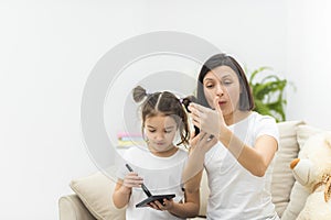 Photo of little daughter helping her young mother with the make up.