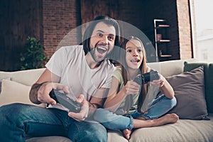 Photo of little funny lady amazed handsome dad sit cosy sofa good mood holding joystick playing video games excited