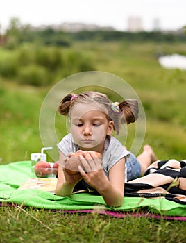 A photo of a little girl laying on a blanket and having a picnic