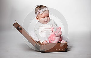 Photo of little girl sitting in old suitcase