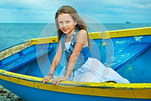 Little cute girl in a boat on the beach, vacation day.