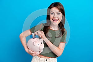 Photo of lovely cheerful girl toothy smile hold put dollar bill money bank pig isolated on blue color background