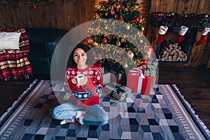 Photo of lovely dreamy jolly girl wear red ornament jumper sit on floor hold morning tradition tasty cacao magic season